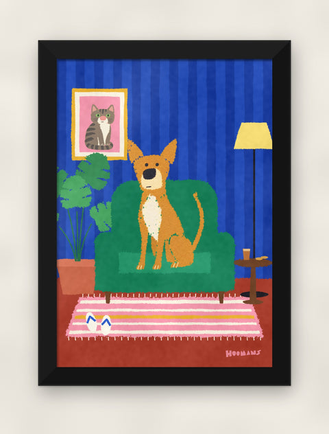 Indie in the Armchair art print in a black frame on a plain wall, front view
