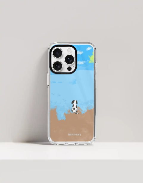 Hoomans Out of Office iPhone case — hand-painted spotted dog on a beach facing the sea, on iPhone 16 Pro mockup