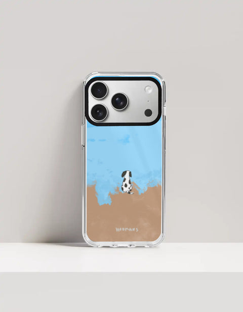 Hoomans Out of Office iPhone case — hand-painted spotted dog on a beach facing the sea, on iPhone 17 Pro mockup
