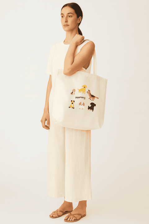 Woman holding a tote bag with dog illustrations on a white background