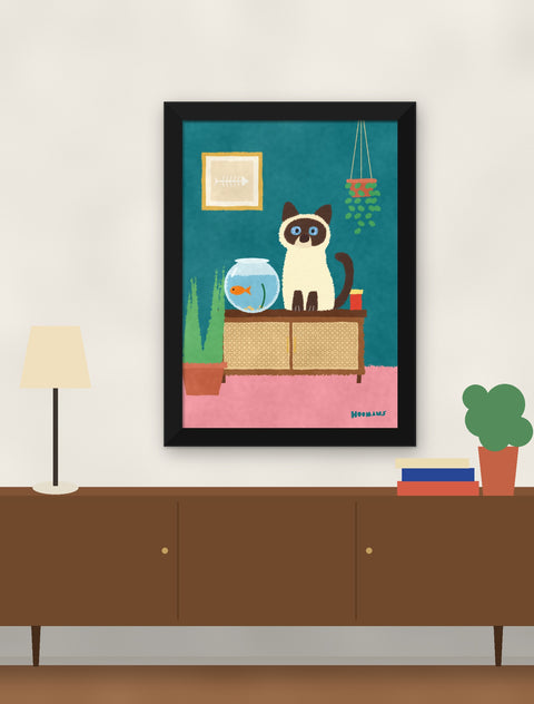 Black framed siamese cat poster hung above a walnut console with a lamp, books and a plant