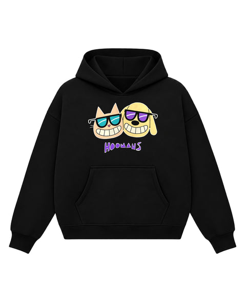 Black boxy hoodie with a peach cartoon cat and a yellow cartoon dog cheek to cheek, both in sunglasses and grinning, above a purple HOOMANS wordmark, front flat lay