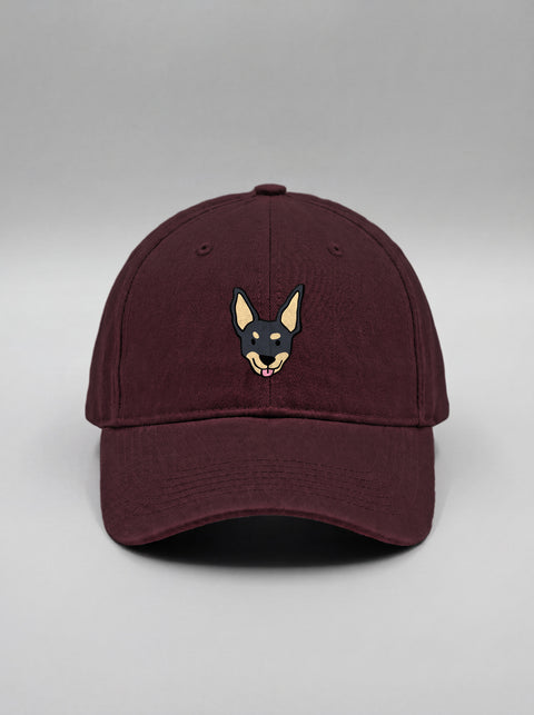 Maroon baseball cap with embroidered black indie dog face, front view