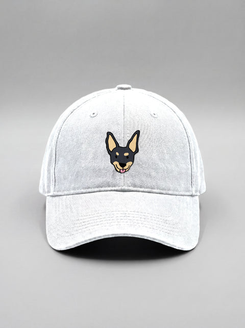White baseball cap with embroidered black indie dog face, front view