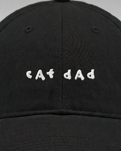 Close-up of the embroidered white cat dad lettering on the front of the black cap