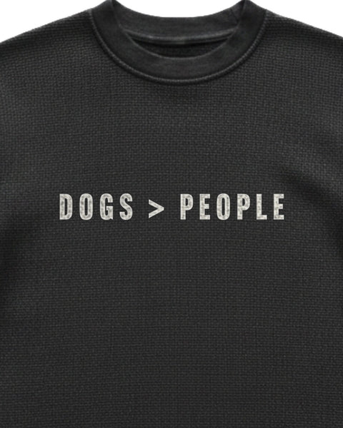 Close up of the DOGS > PEOPLE chest print on black waffle knit, showing the knit texture through the ink