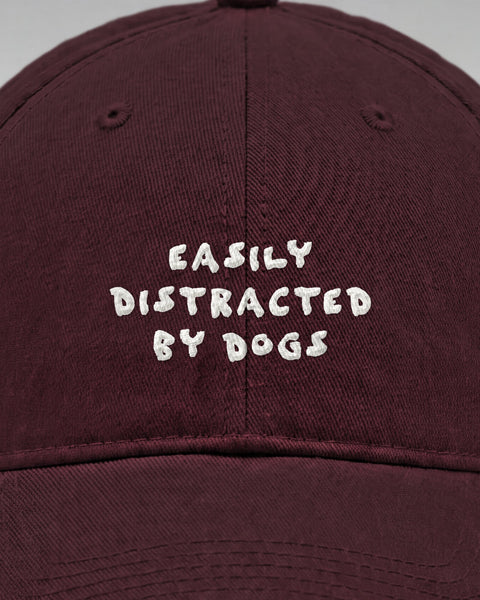 Close-up of the embroidered Easily Distracted By Dogs lettering on the front of the maroon cap