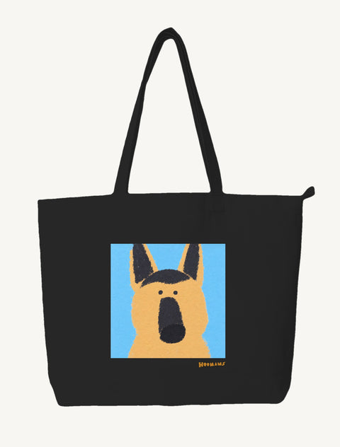 Black large canvas tote bag with a flat colour German Shepherd face on a sky blue block and an amber Hoomans wordmark, front view