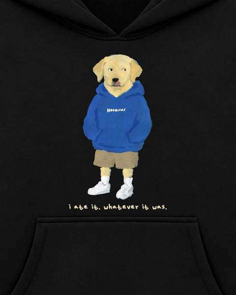 Close up of the chest print: a yellow labrador in a cobalt HOOMANS hoodie, tongue out, above 'i ate it. whatever it was.'