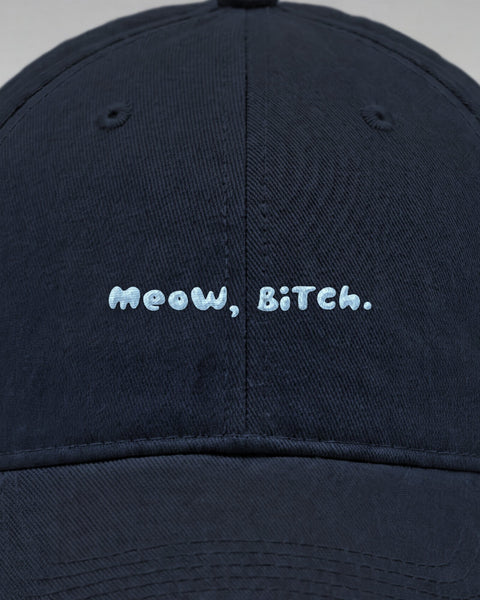 Close-up of the embroidered light blue Meow, Bitch. lettering on the front of the navy cap