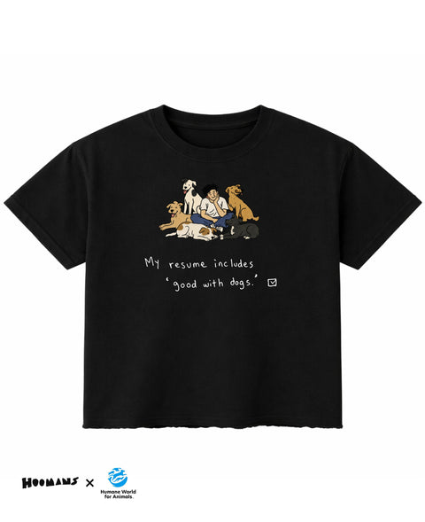 My Resume Speaks boxy fit tee in black, a hooman sitting among five indie dogs above My resume includes good with dogs and a ticked box, front view, Hoomans x Humane World for Animals India lockup