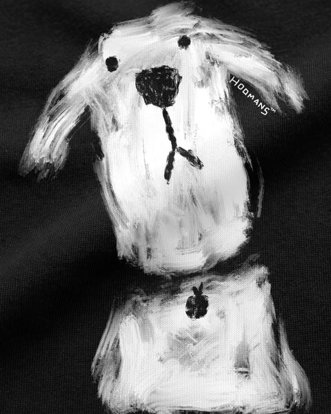 Close-up of the brushy white dog with the small hoomans signature printed on fitted black cotton jersey