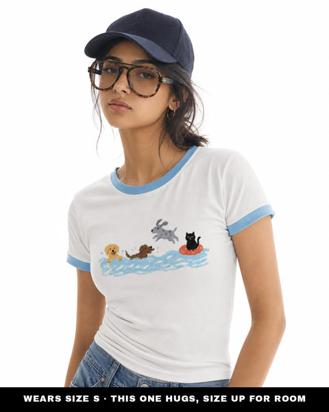 Model wearing the Swim Club white ringer tee with sky blue trim in size S, fitted, with the crayon swimming dogs and cat print across the chest