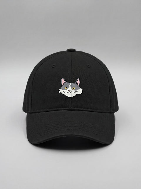 Black baseball cap with embroidered white and grey cat face, front view