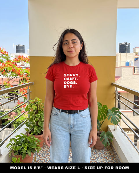 Model wearing the Sorry Can't Dogs Bye red baby tee in size L, 5 foot 5, standing on a balcony